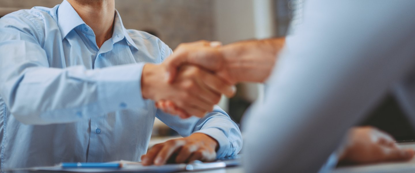 Handschlage über einem Tisch von zwei Männern