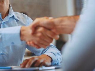 Handschlage über einem Tisch von zwei Männern