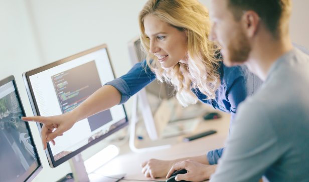 Blonde woman points at screen during workplace conversation